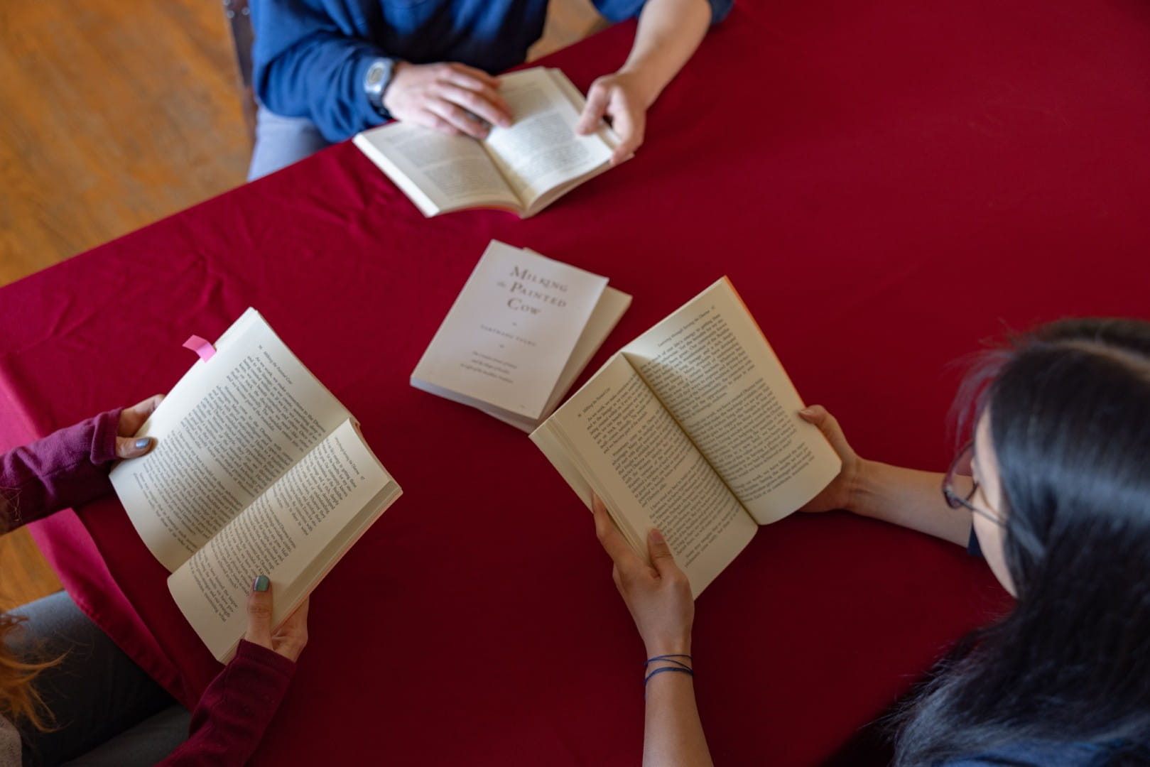 Students reading Tarthang Tulku's books together around a red table during a Nyingma Institute study session.