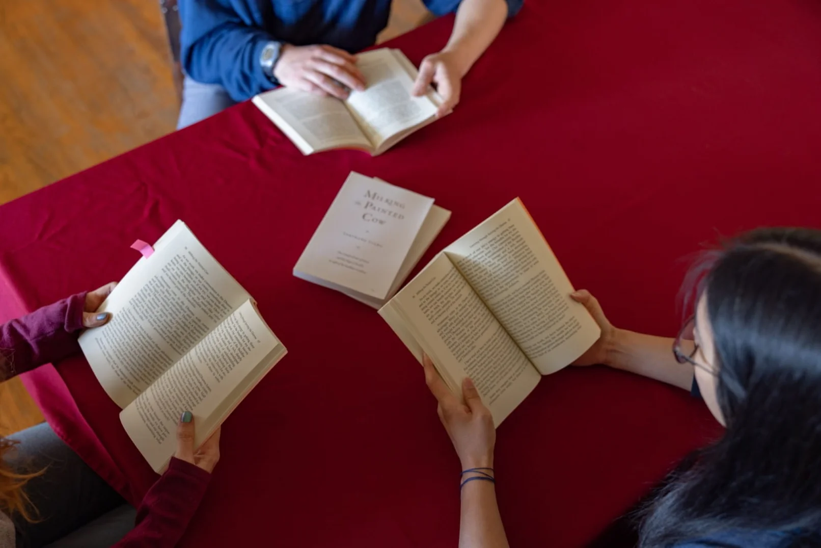 Students reading Tarthang Tulku's books together around a red table during a Nyingma Institute study session.